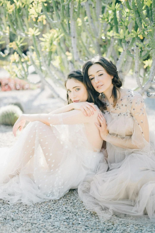 a young woman sitting next to another young woman on the ground