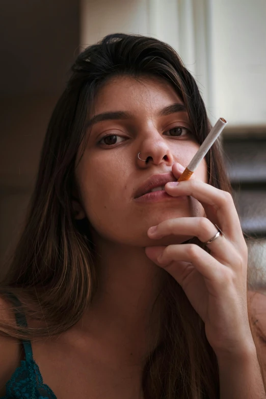 a beautiful young lady smoking a cigarette in front of her face