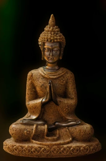 a buddha statue with its legs crossed with a black background