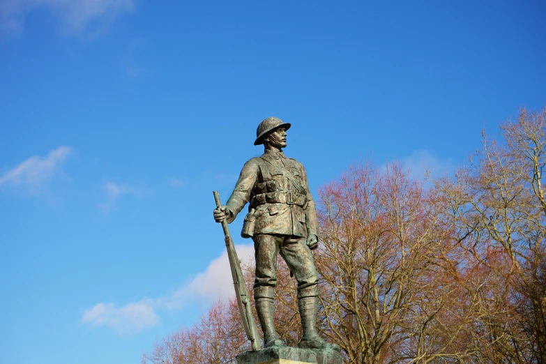 a statue of a soldier holding a rifle near a tree