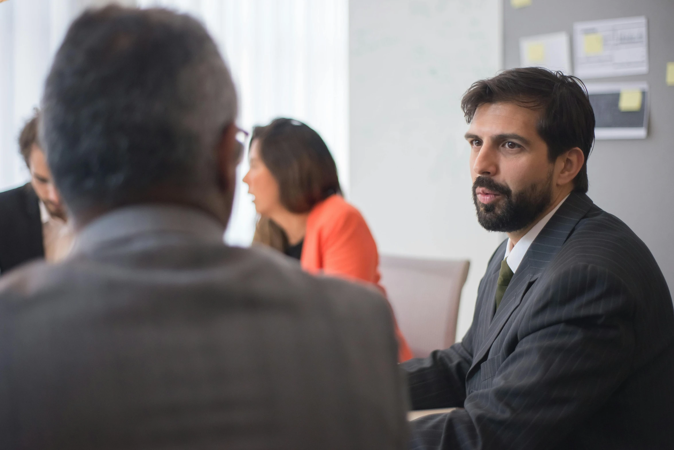 a man in a suit sitting at a table with other people