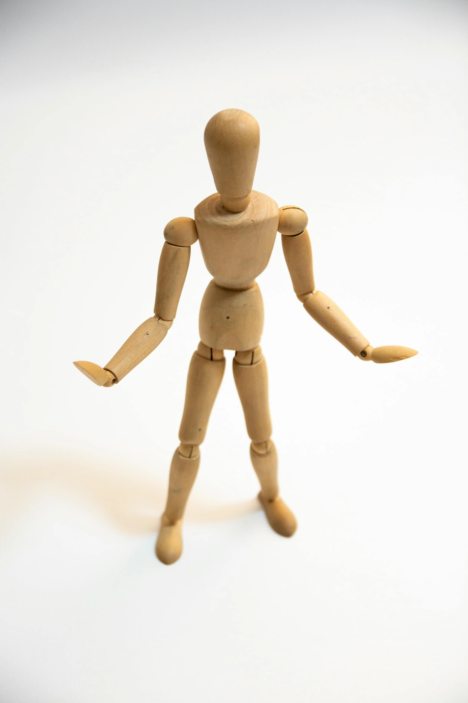 a wooden mannequin figure stands with hands outstretched