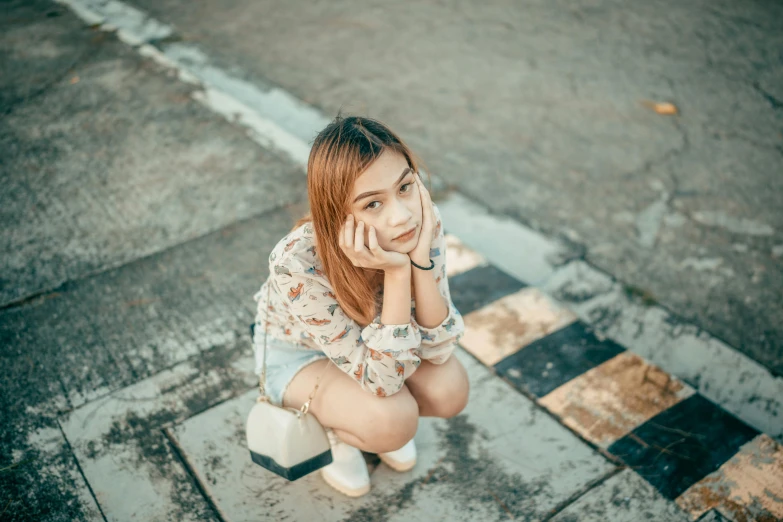 a girl sitting on the ground talking on a phone