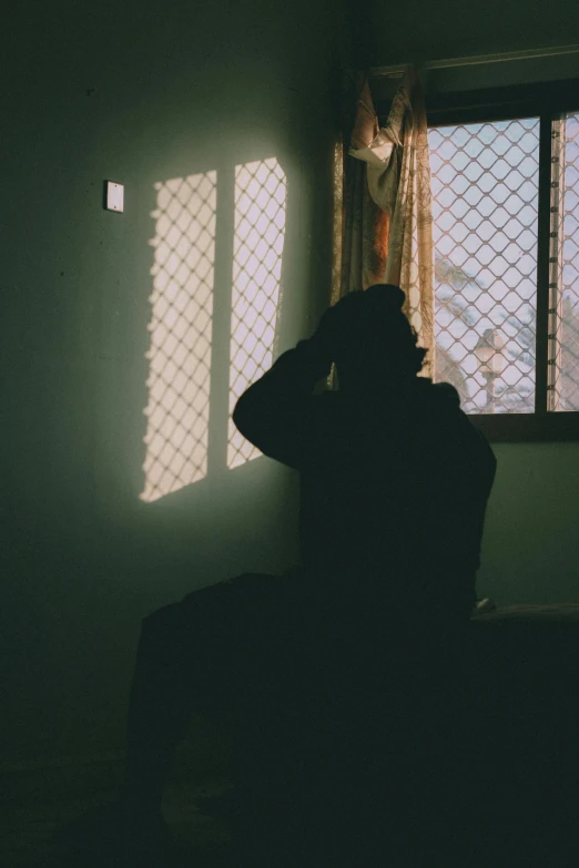 silhouette of man sitting by window at dark home