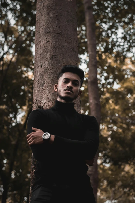 young man leaning against a tree and smiling