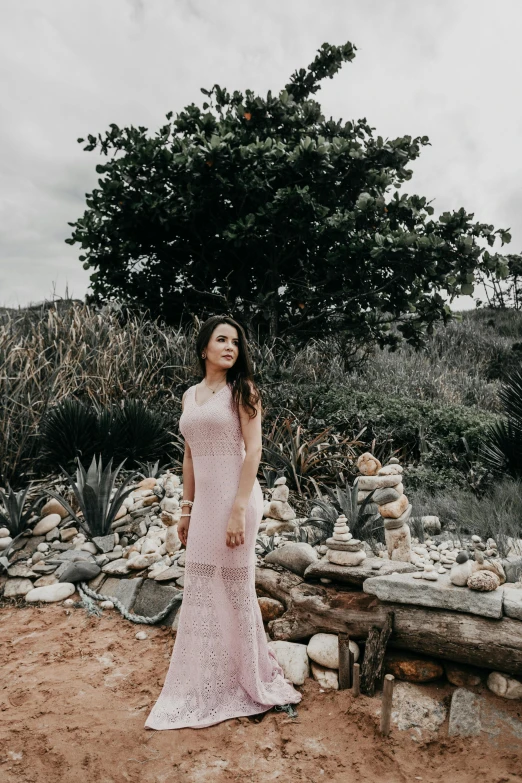 a woman stands in the desert near rocks and trees