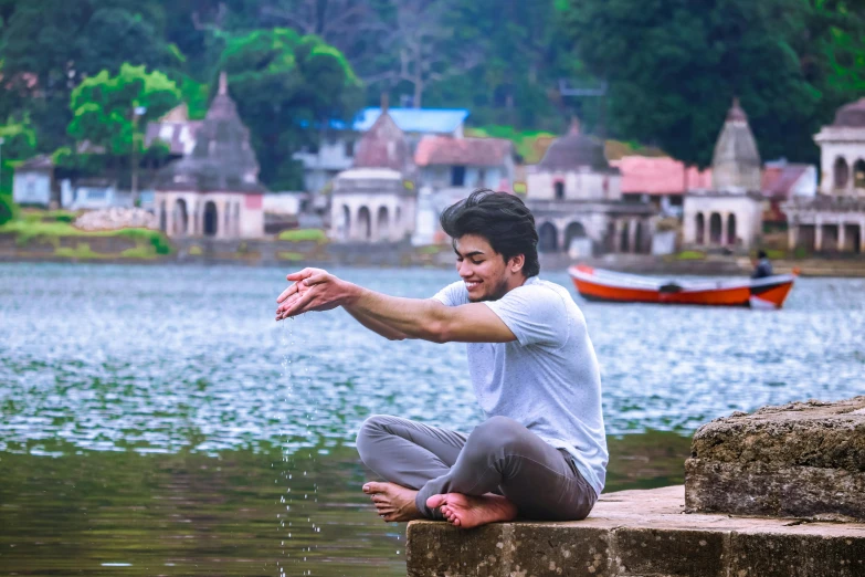 the man is sitting on the pier near a body of water