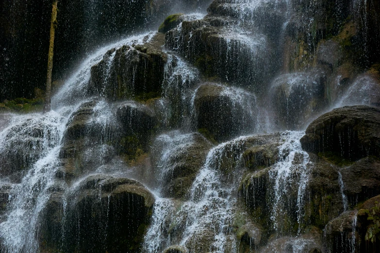 waterfall coming down from the mountain with green grass and trees around