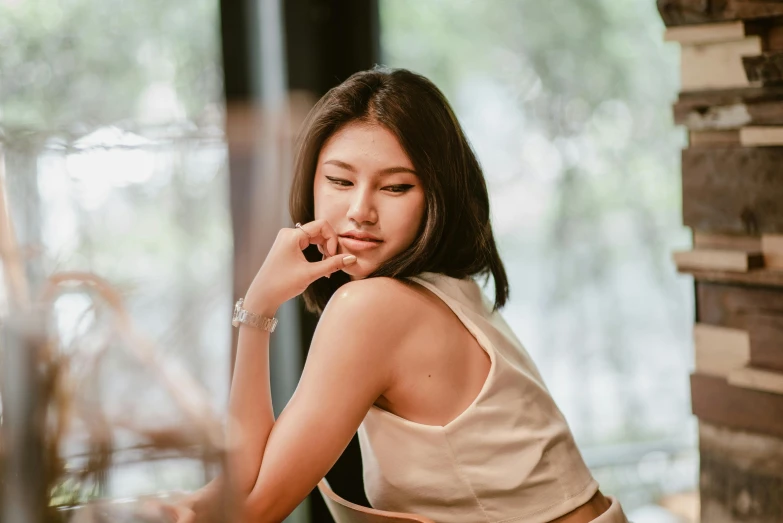 a woman sitting down looking bored with her hand on her chin