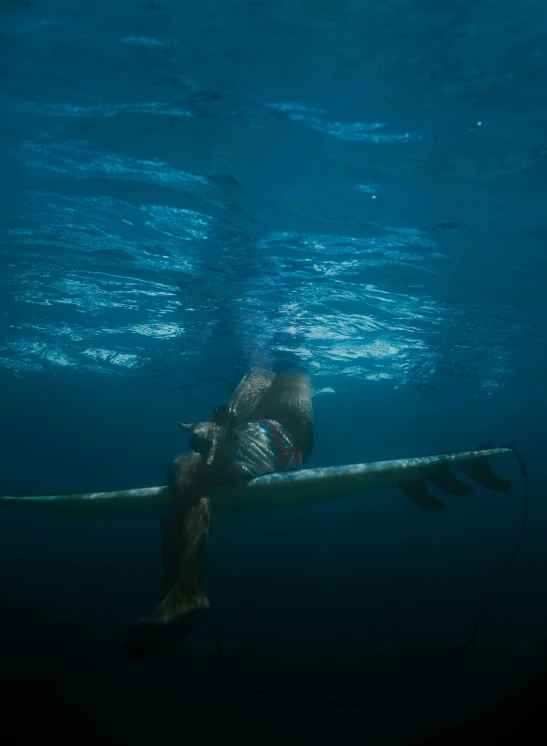 a man swimming under water with his surfboard