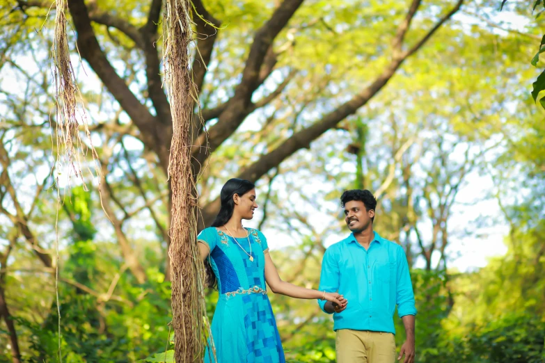 couple holding hands next to large tree