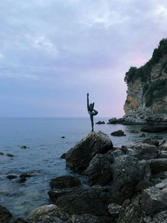 there is a man standing on top of a rock by the ocean