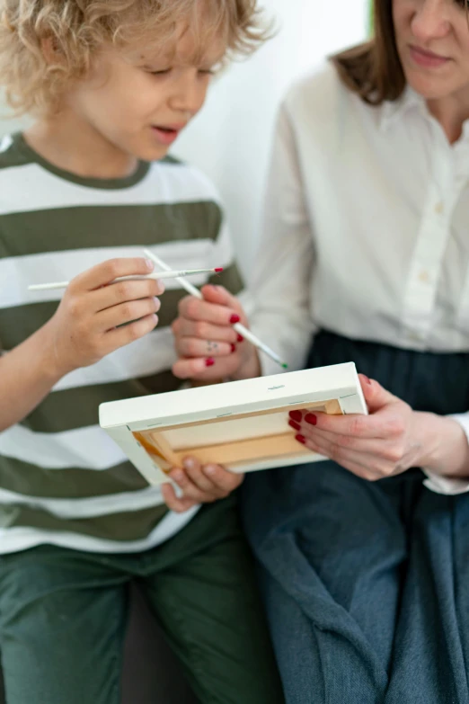 there is a little boy sitting on the lap of a woman holding soing with toothbrushes