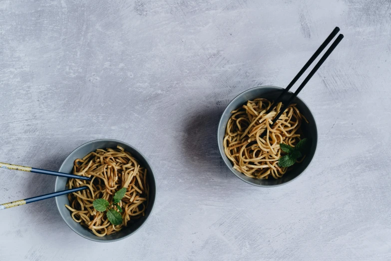 two bowls of noodles on a white table