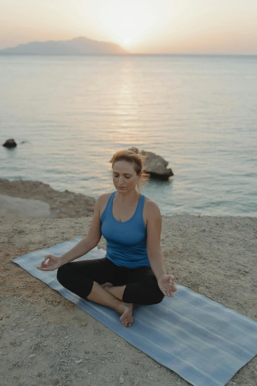 a woman practices a yoga pose on the beach