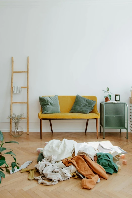 a room with clothing on the floor and a couch and wooden furniture