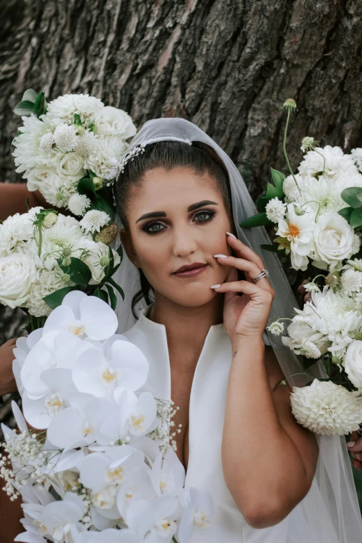 a bride posing near the wedding bouquet while holding a cell phone