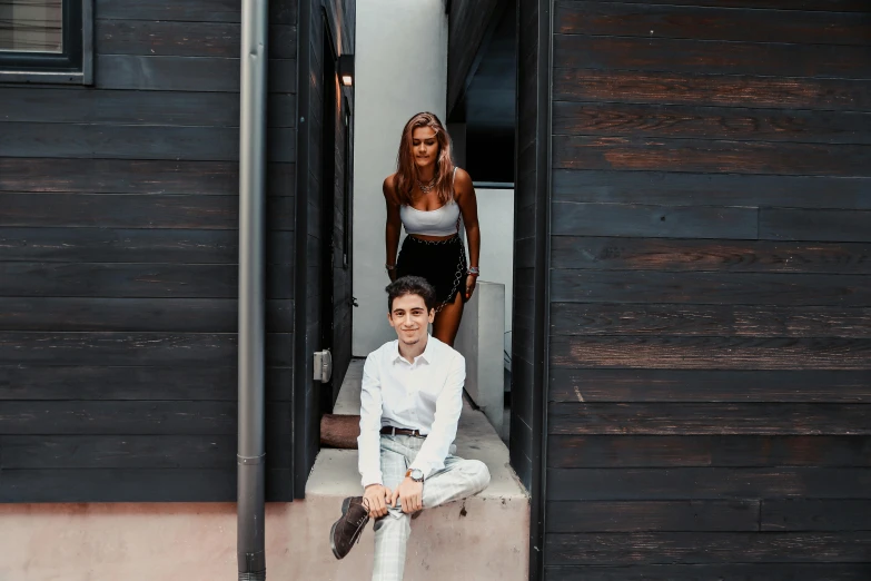 a man is sitting on a ledge near another woman