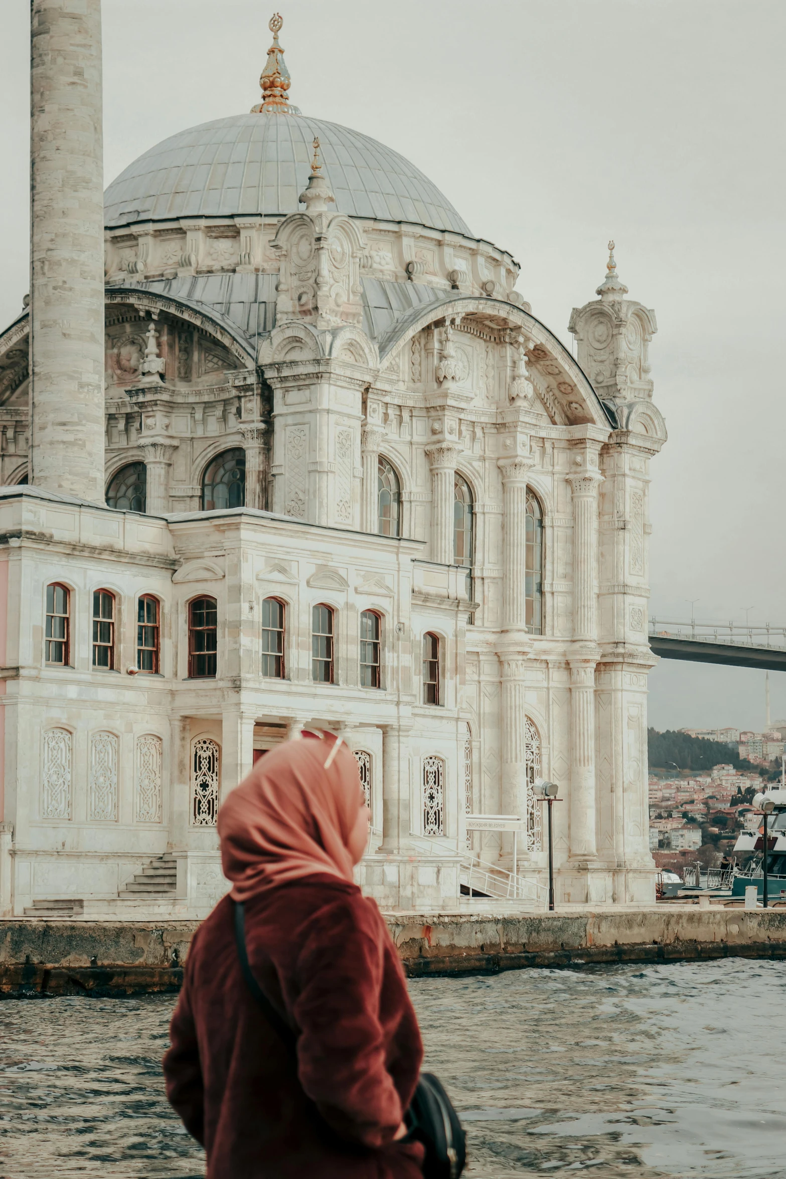 the person in a red coat is looking at an old building