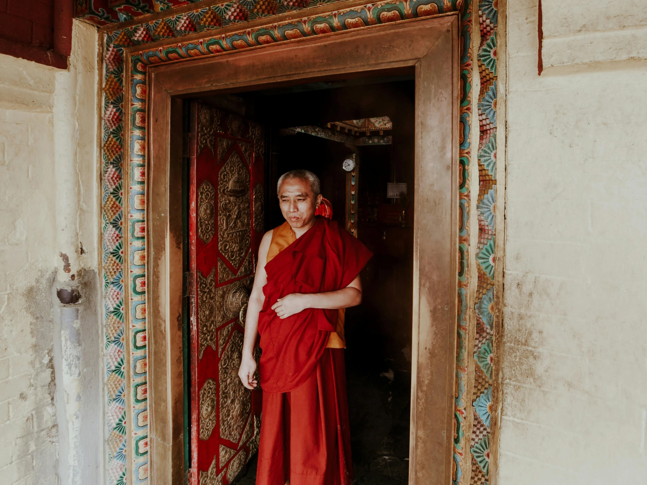 a man in an orange monk outfit stands at the door of a building