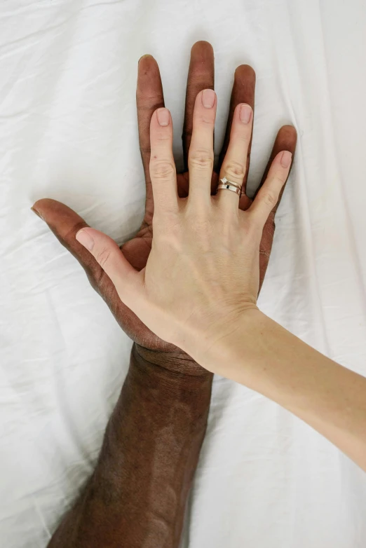 a person wearing a gold wedding ring is palm over the bed