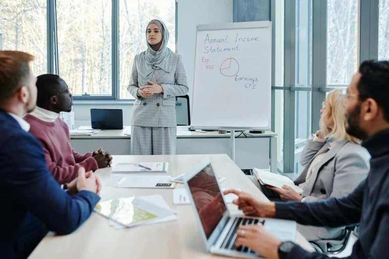 a group of business people listening to a woman at a board room