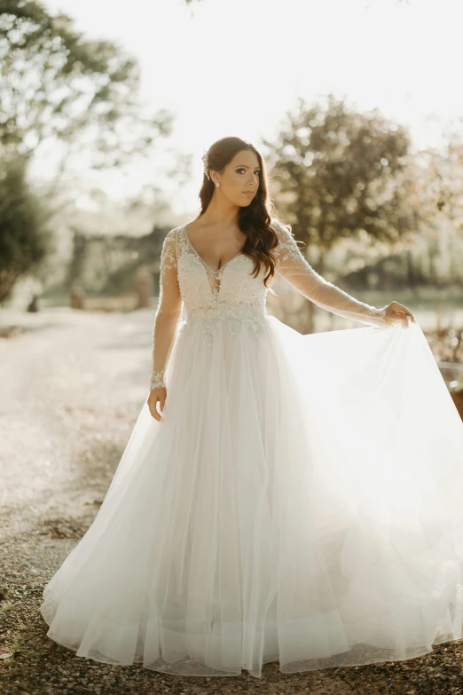 a woman wearing a long white dress standing in the road