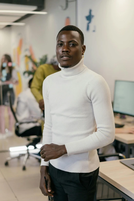 an african man standing next to his desk in a large room