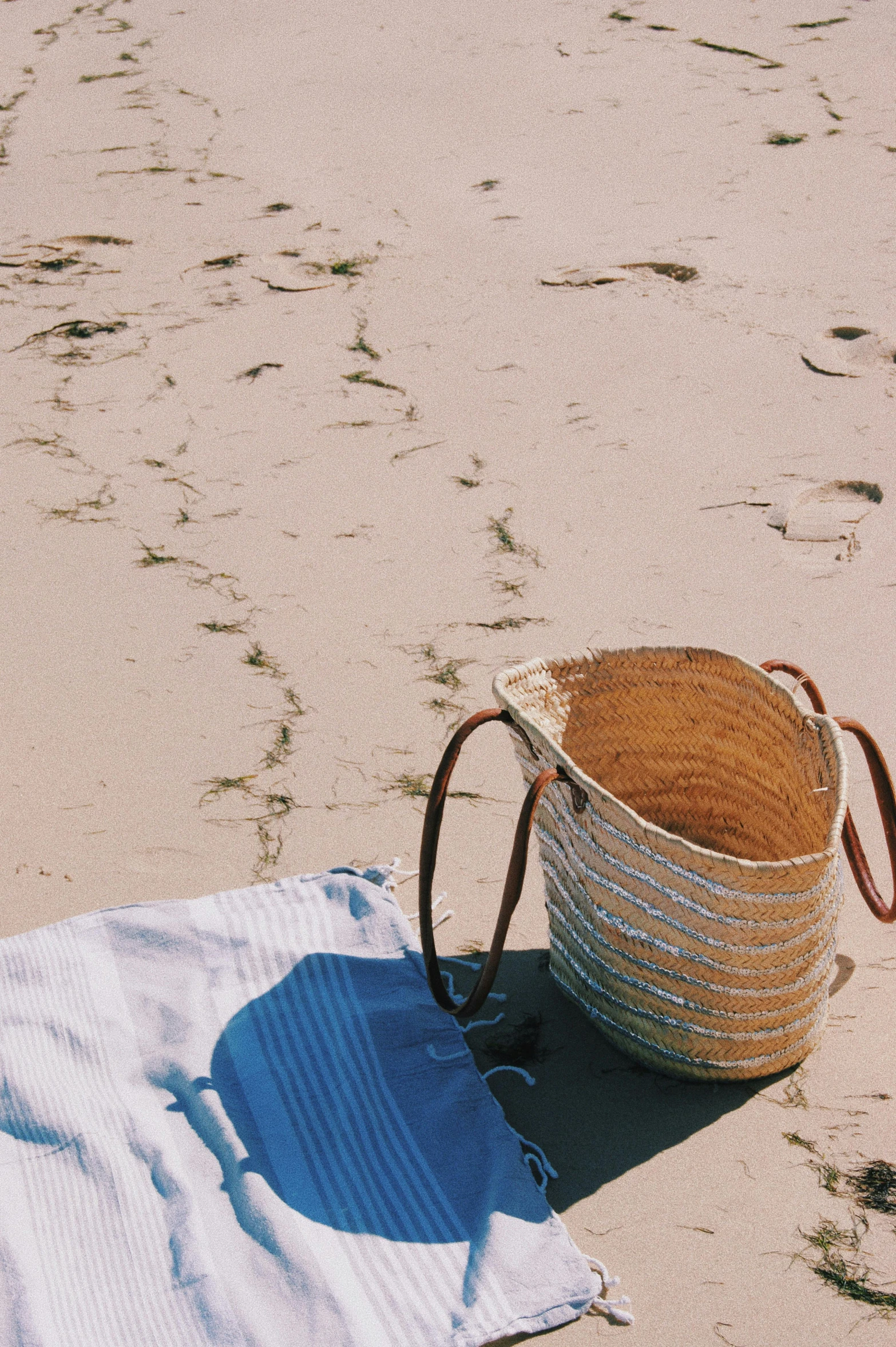 straw basket on beach with blue towel and white towel