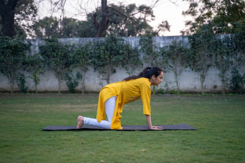 a young woman is practicing yoga in the park