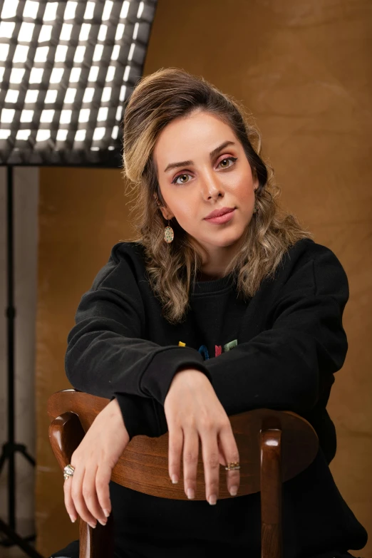 woman in black sweater sitting on chair near pographer