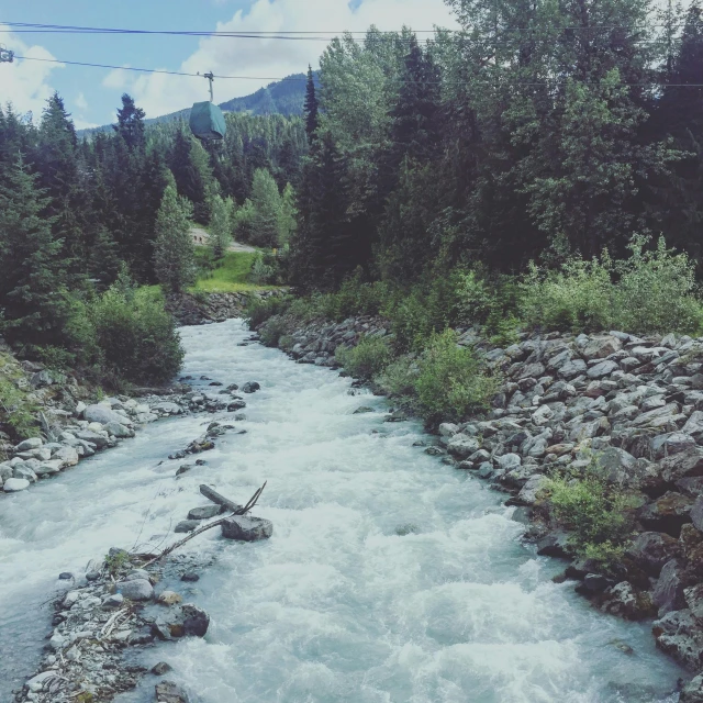 a fast moving river running between rocks in the woods