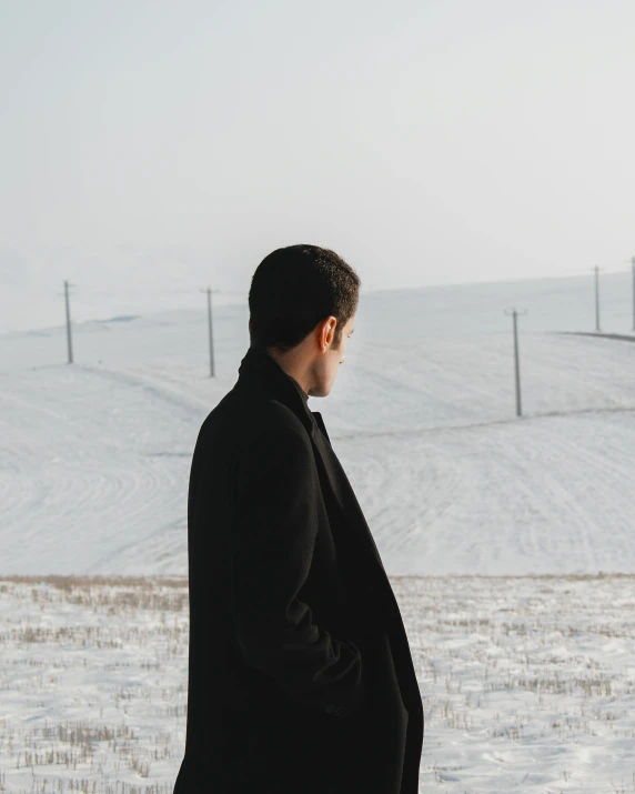 a man looking out at the snow and the mountains in the distance