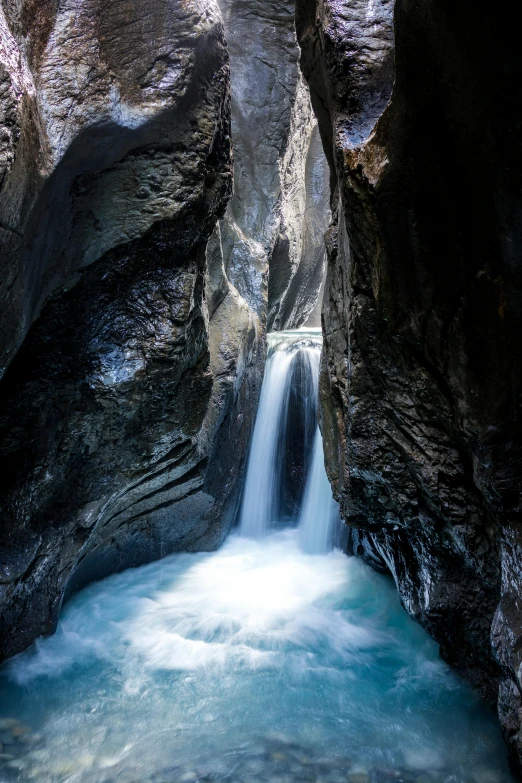 a waterfall is surrounded by rocks, which give it water a blue hue