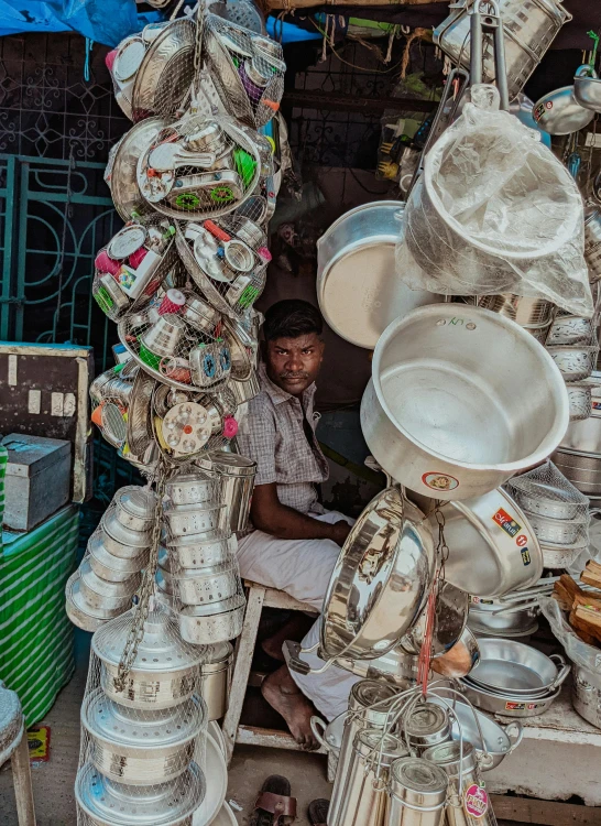 a man sits in front of a pile of silver pans