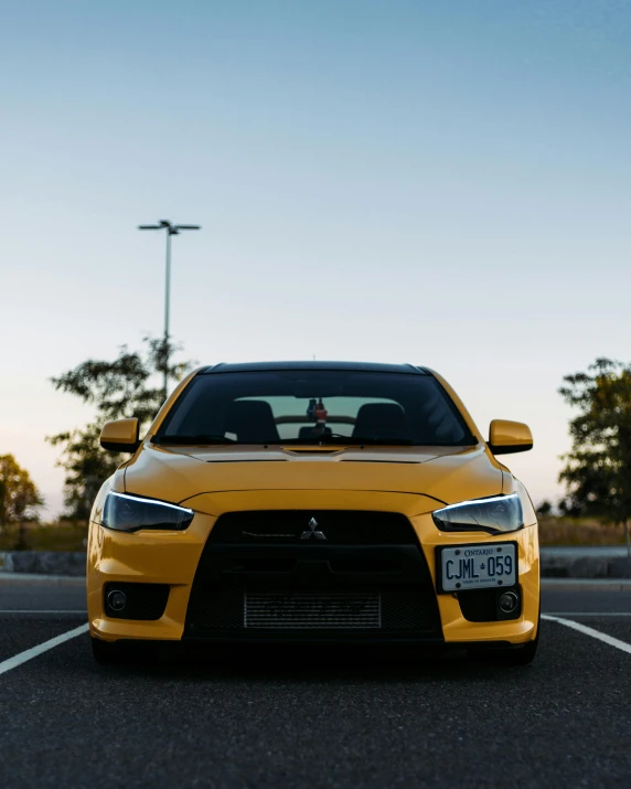 the front view of a yellow car parked in a parking lot