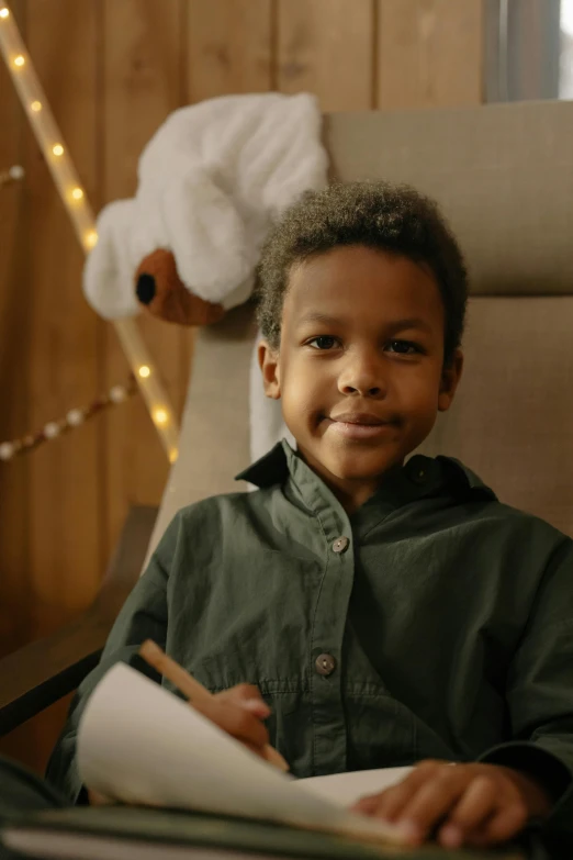 a little boy is sitting at a table writing on paper