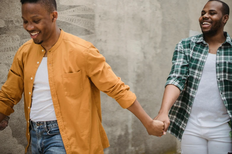 two people holding hands in front of a wall