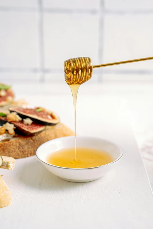 a bowl filled with honey next to sliced bread