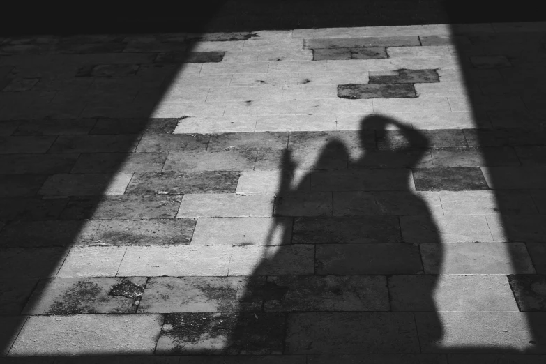 a shadow of a person standing on the sidewalk