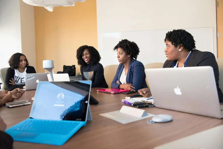 people gathered around a conference table to look at the computers