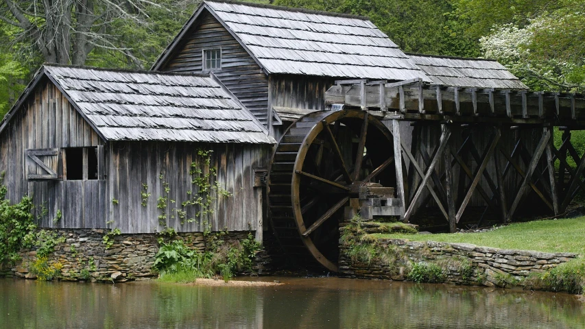 a water mill sits on top of a small body of water
