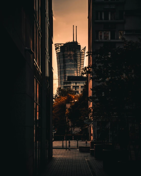 a city street is dark with buildings and the sun setting