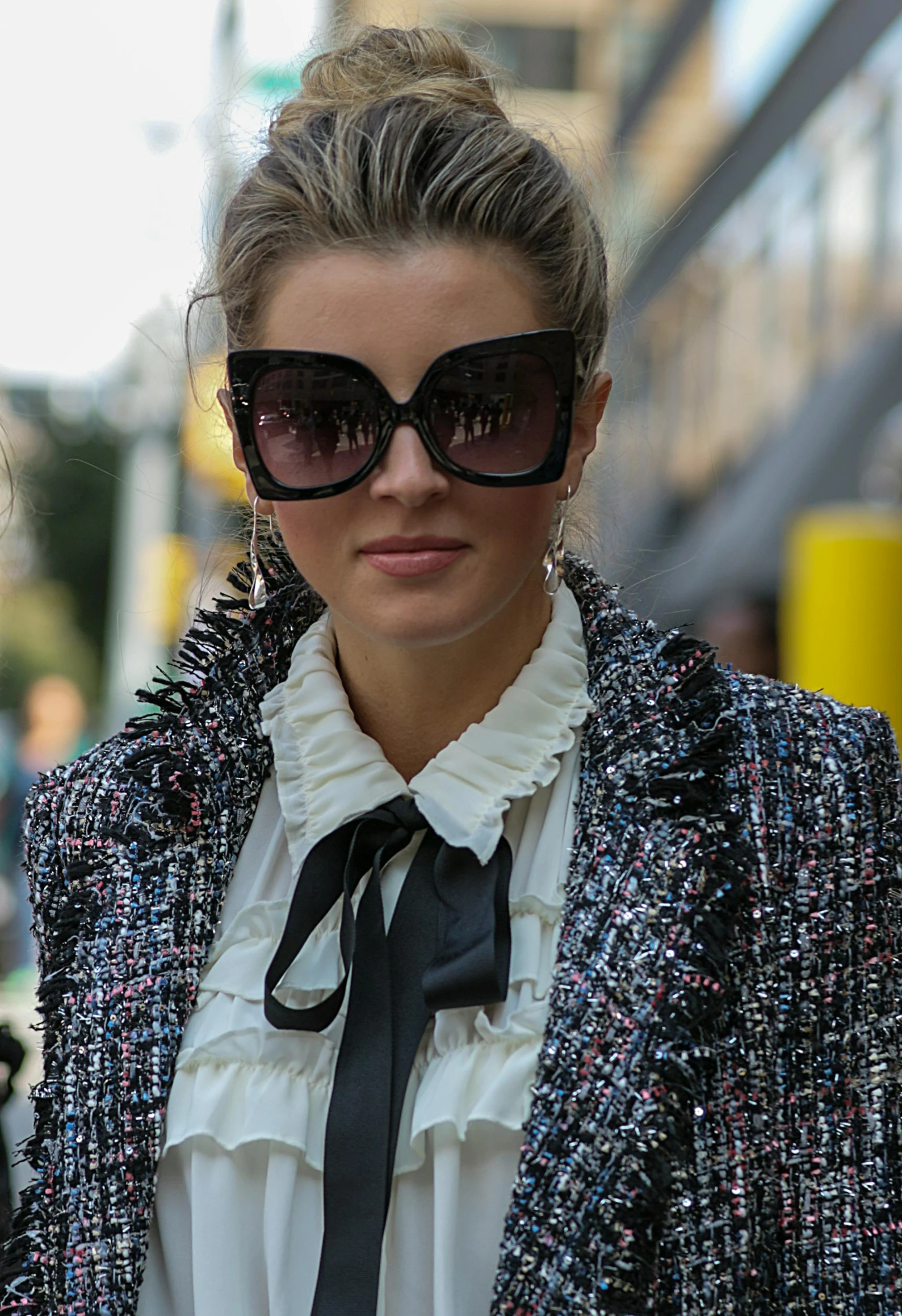 the woman wearing black sunglasses is posing on a street