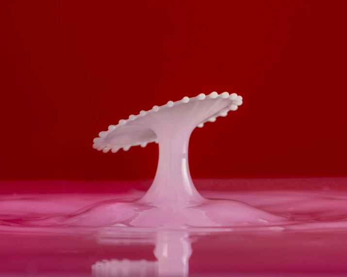 a liquid drop in the middle of pink water