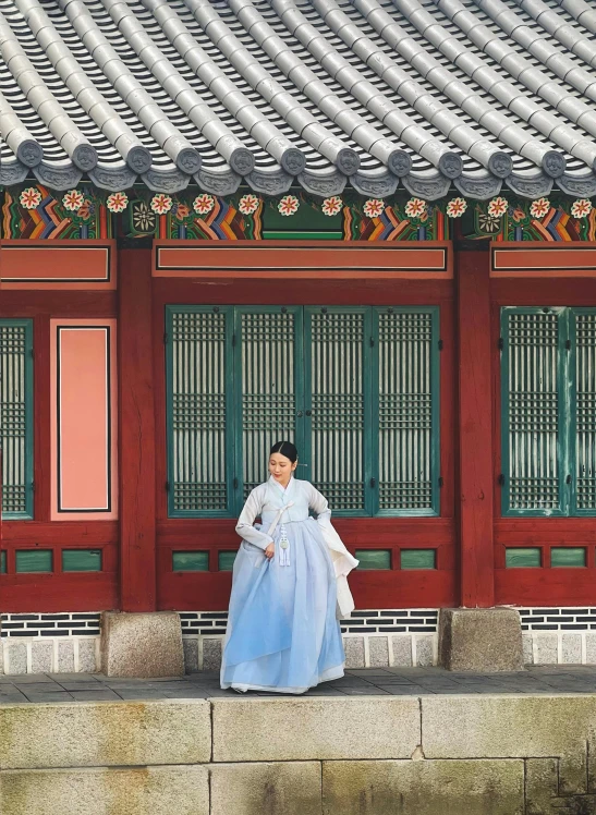 the woman stands in front of the traditional building