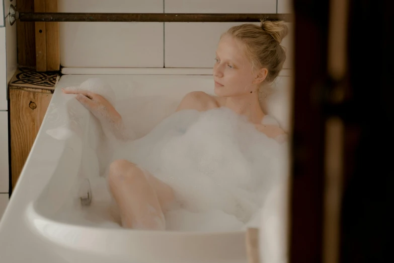 a woman sitting in a bubble bathtub with water coming out of her mouth