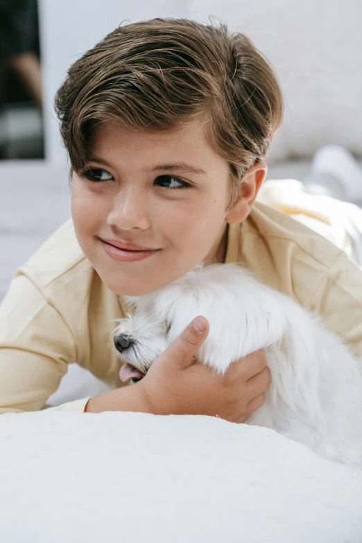 the boy is holding his white dog and posing