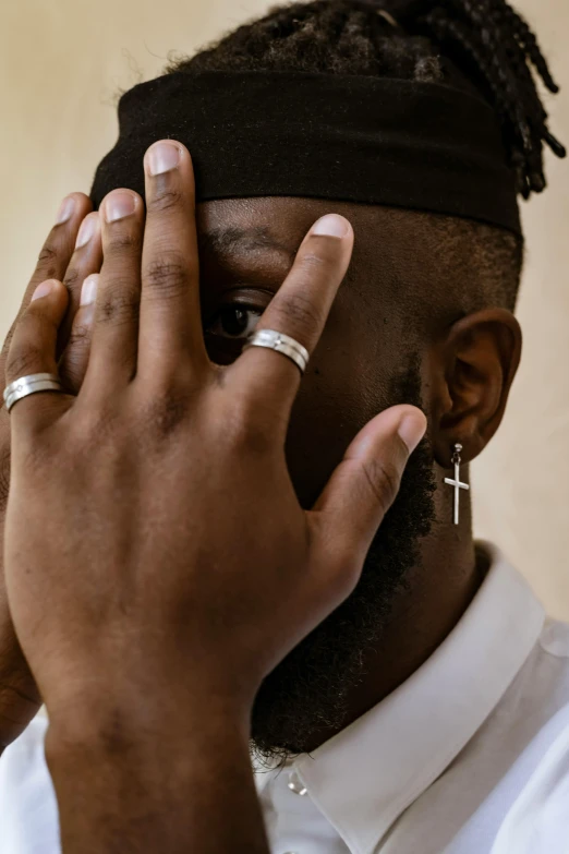 a black man wearing two rings holds his fingers to his ear