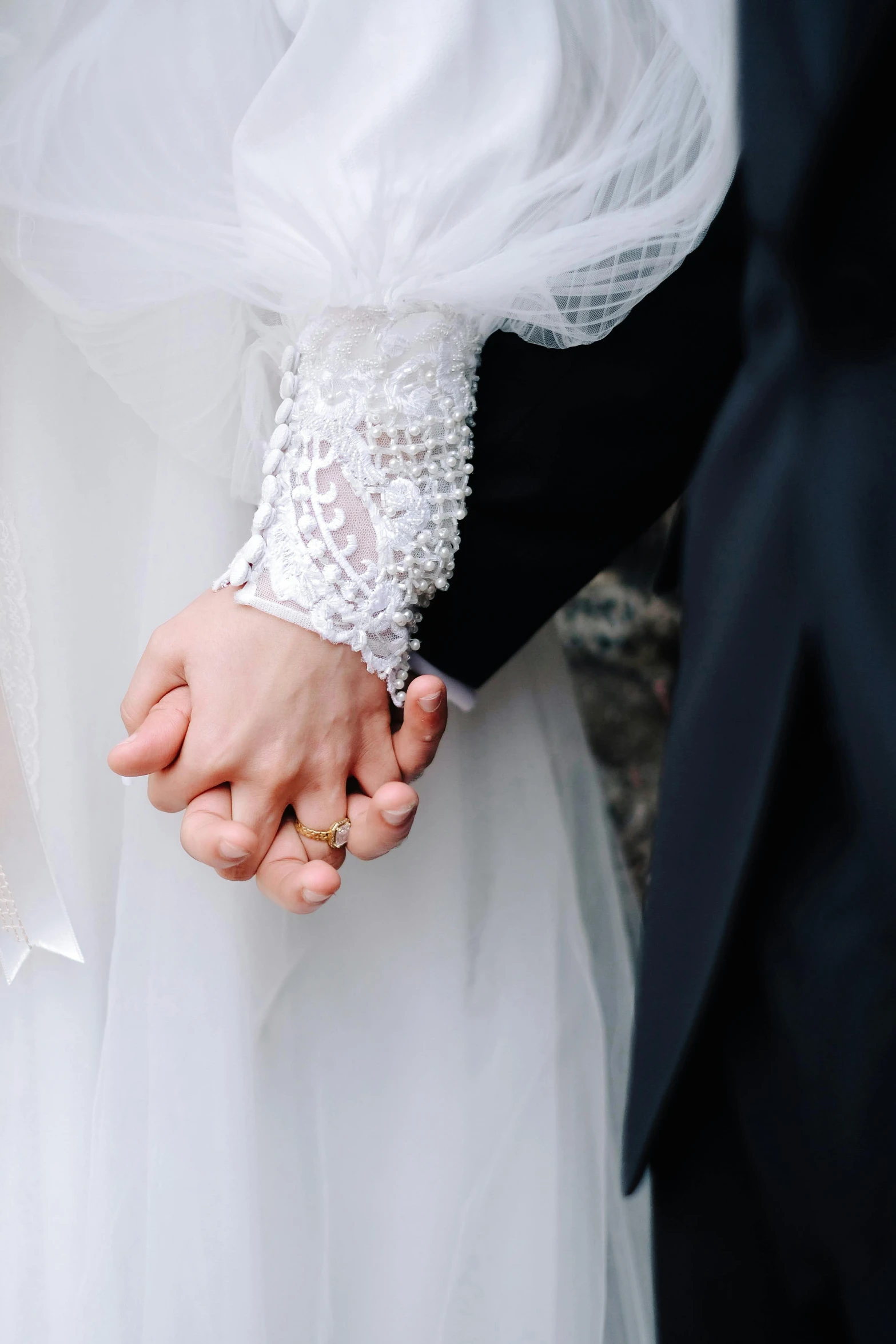 a couple hold hands close together as the bride puts a ring on her groom's finger